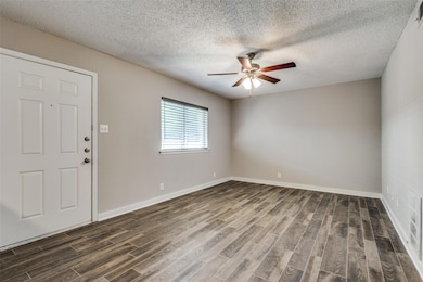 Spare room with baseboards, dark wood-type floorin