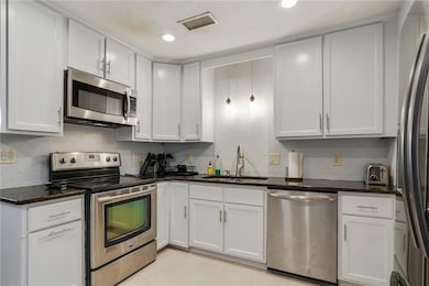 Kitchen with stainless steel appliances, a sink, white cabinetry, and recessed lighting