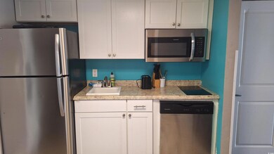 Kitchen with appliances with stainless steel finishes, white cabinets, and light stone counters