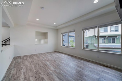 Spare room with wood finished floors, a tray ceiling, and recessed lighting