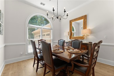 Dining room featuring a chandelier, plenty of natural light, light wood finished floors, and crown molding