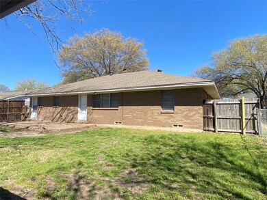 Back of house with brick siding, fence, a lawn, an