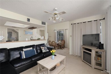 Living room with light carpet, visible vents, a textured ceiling, and a ceiling fan