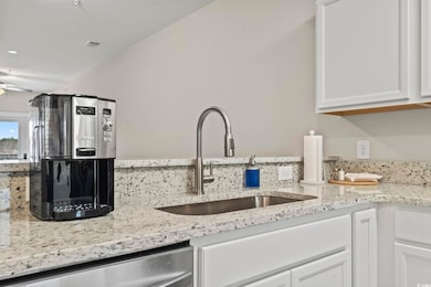 Kitchen featuring dishwasher, sink, white cabinets