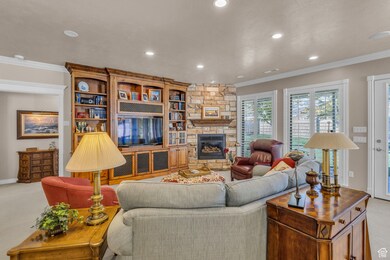 Living area featuring crown molding, stone surround fireplace, and recessed lighting