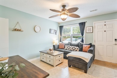 Tiled living room with ceiling fan and a textured 