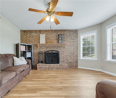 Living area with a ceiling fan, baseboards, a fire