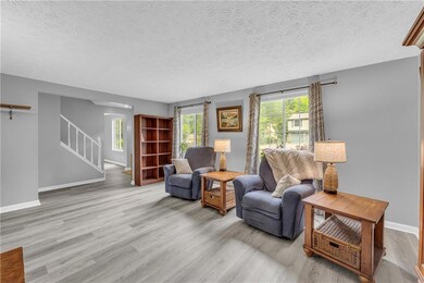 Living area featuring stairs, wood finished floors, baseboards, and a textured ceiling