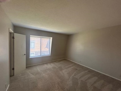 Carpeted empty room featuring a textured ceiling and baseboards