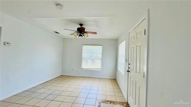 Empty room featuring light tile patterned floors, ceiling fan, a smoke detector, and baseboards
