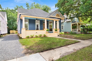 View of front of home with covered porch, roof with shingles, a front lawn, and brick siding