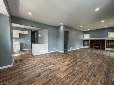 Unfurnished living room with dark hardwood / wood-style flooring and a brick fireplace