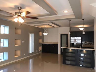 Kitchen featuring light tile patterned flooring, fridge, light countertops, a raised ceiling, and dark cabinets