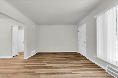 Spare room with ornamental molding, plenty of natural light, and light hardwood / wood-style flooring