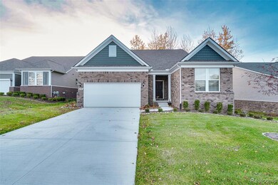 Single story home featuring concrete driveway, a front yard, brick siding, and an attached garage