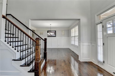 Entryway with dark wood-type flooring, crown moldi