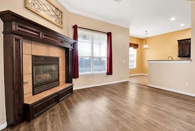 Unfurnished living room featuring dark wood finished floors, baseboards, a tile fireplace, recessed lighting, and crown molding