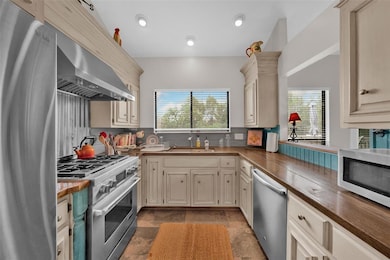 Kitchen with appliances with stainless steel finishes, healthy amount of natural light, wall chimney exhaust hood, decorative backsplash, and recessed lighting