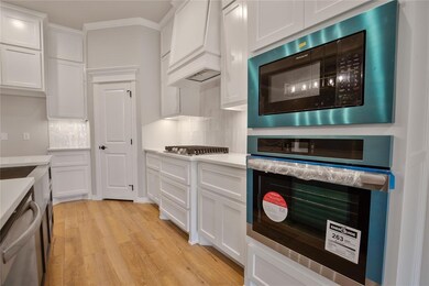 Kitchen with custom exhaust hood, light hardwood /