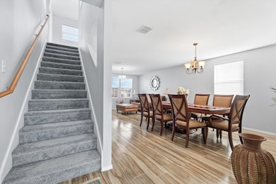 Dining area with stairway, healthy amount of natural light, light wood-type flooring, and a chandelier