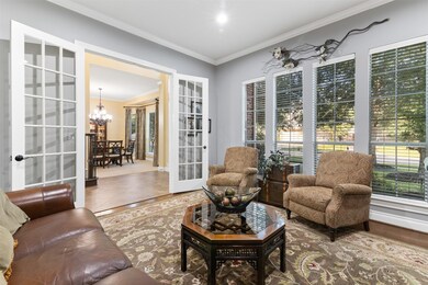 The study has French doors, high ceilings, crown molding and a wall of windows overlooking the front yard.