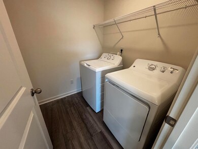 Clothes washing area with dark hardwood / wood-sty