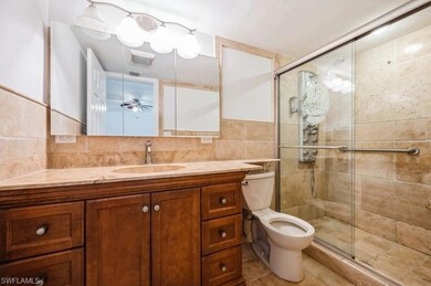 Bathroom featuring tile walls, vanity, a shower stall, backsplash, and ceiling fan