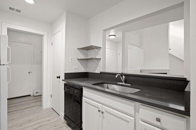 Kitchen featuring dishwasher, a sink, dark counte