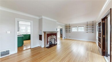 Living room featuring a brick fireplace, light hardwood floors, and ornamental molding