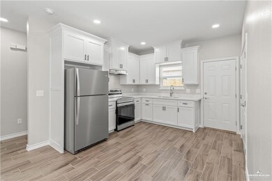 Kitchen with light countertops, white cabinets, stainless steel appliances, light wood finished floors, and a sink