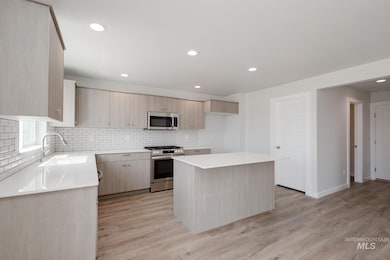 Kitchen featuring light brown cabinets, appliances with stainless steel finishes, a kitchen island, recessed lighting, and backsplash