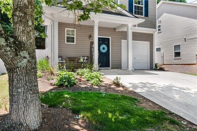 View of exterior entry with a garage, driveway, and covered porch