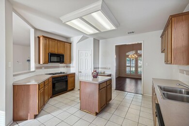 Kitchen featuring light tile flooring, backsplash, a notable chandelier, black appliances, and sink