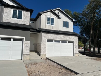 View of front of house featuring stone siding, a garage, stucco siding, concrete driveway, and board and batten siding
