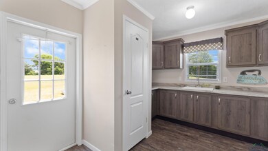 Kitchen with crown molding, dark wood finished floors, and light stone counters