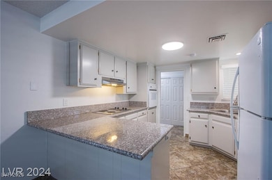 Kitchen featuring a peninsula, white appliances, u