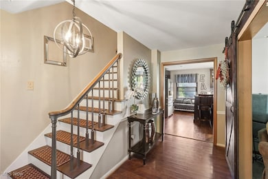 Stairway with a barn door, wood finished floors, and a chandelier