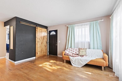 Sitting room with a barn door, wood finished floors, and a textured ceiling