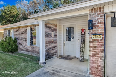 Doorway to property featuring a porch, brick siding, and a lawn