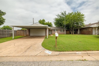 View of front of home featuring brick siding, driveway, a carport, and an attached garage