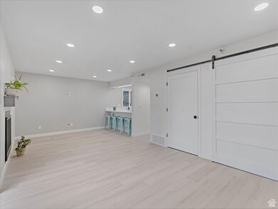 Unfurnished living room with recessed lighting, a barn door, and light wood-style flooring