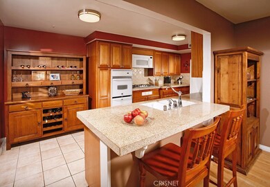 Remodeled family kitchen with rich custom mahogany cabinets, granite counter-tops, tiled back-splash, dual basin under-mount sink, decorative faucet, 5-burner gas cooktop, built-in microwave, self-cleaning oven, dishwasher, tiled floors and handy gra