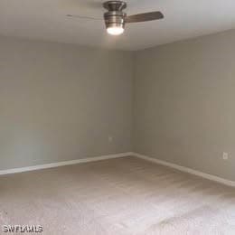 Carpeted spare room with a ceiling fan and baseboa