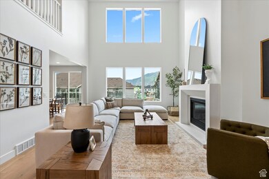 Living area featuring a glass covered fireplace, light wood-type flooring, a high ceiling, and a mountain view