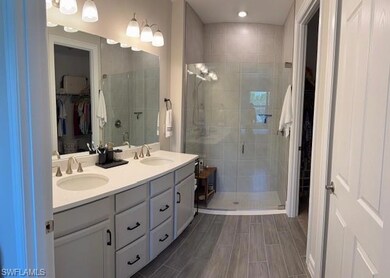 Bathroom with a walk in closet, double vanity, a shower stall, and recessed lighting