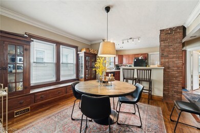 Open-concept Dining room featuring decorative lighting,  hardwood floors, and brick accent wall