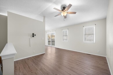 Unfurnished living room with healthy amount of natural light, dark wood finished floors, a textured ceiling, and ceiling fan