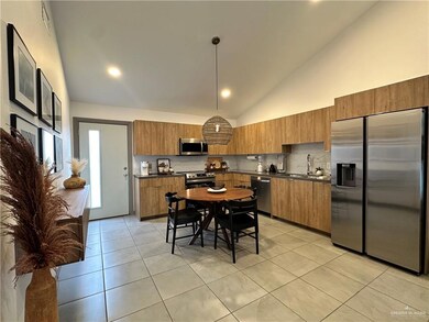Kitchen with stainless steel appliances, dark countertops, brown cabinets, high vaulted ceiling, and recessed lighting