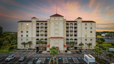 View of apartment building / complex featuring a water view and uncovered parking