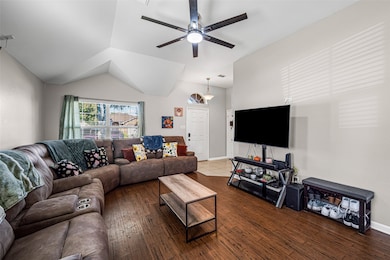 Living area with dark wood-style flooring, vaulted ceiling, and ceiling fan